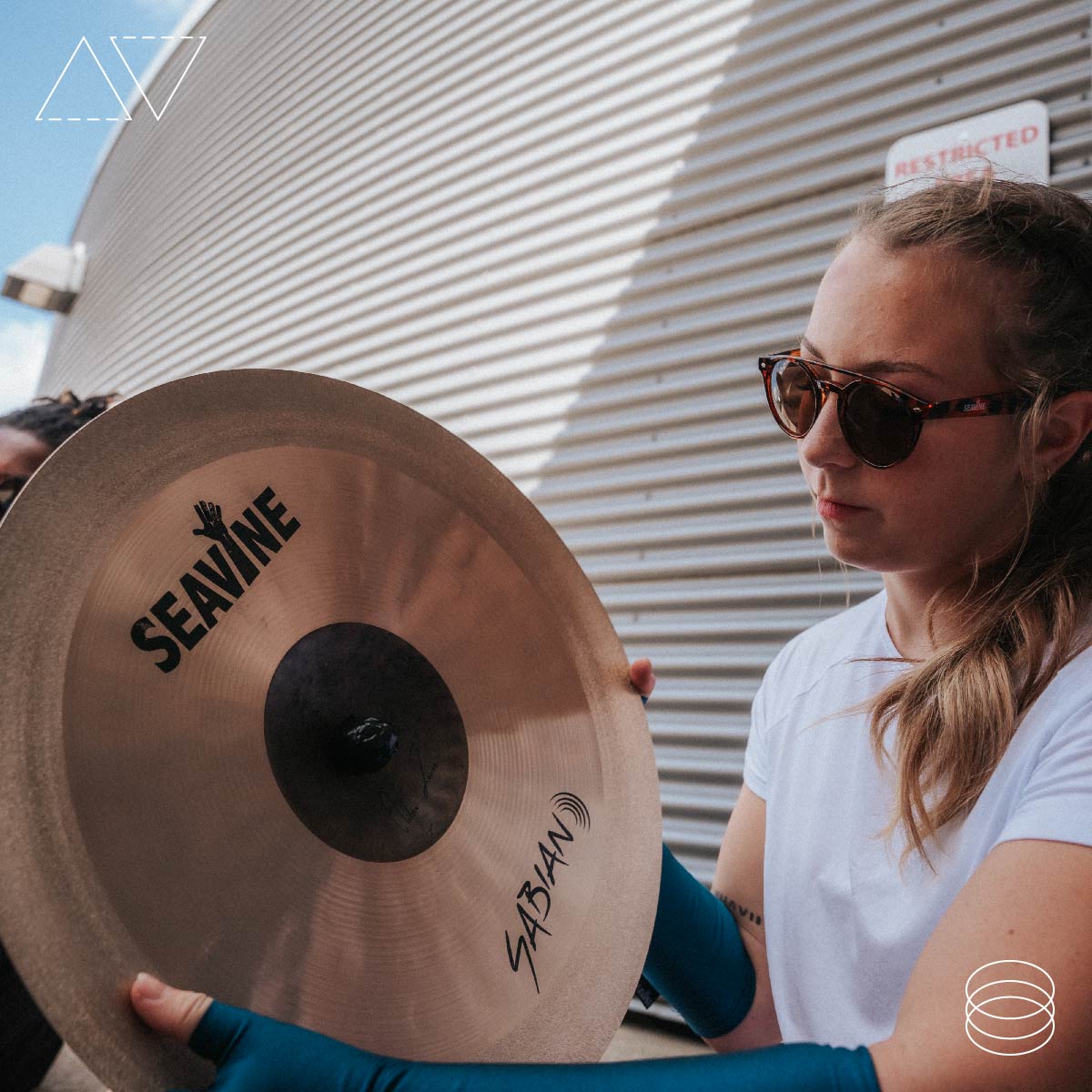 Female marching band student inspecting the AV cymbal by Sabian and Seavine